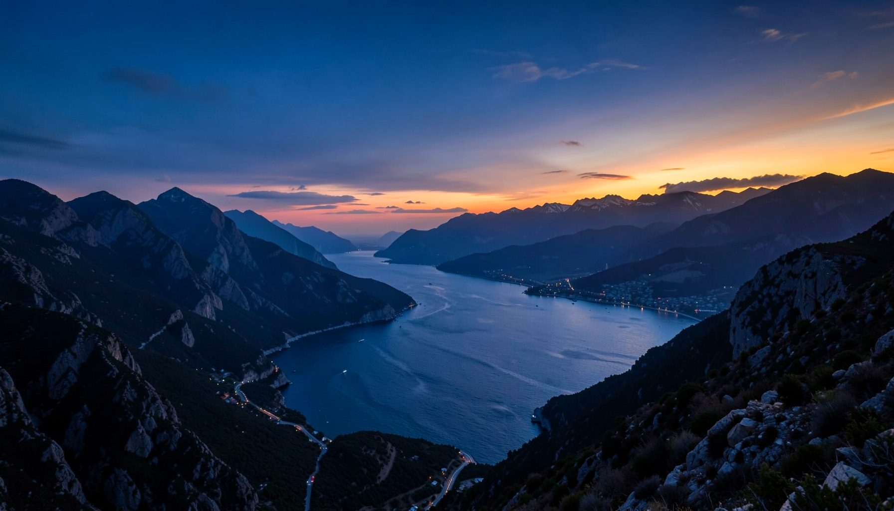 Paisaje de montañas y costa al atardecer con tonos azules profundos y un toque cálido de naranja, ambiente contemplativo